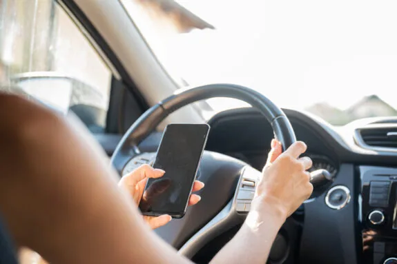 Woman using her mobile phone and texting while driving